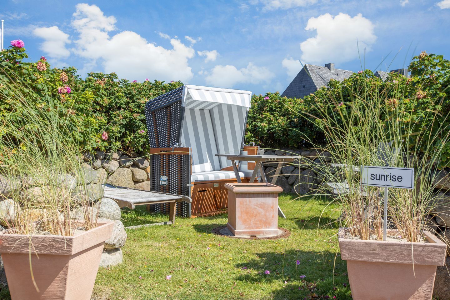 Un jardin agrémenté de mobilier d’extérieur, d’une chaise à rayures et d’un panneau indiquant « lever du soleil ».