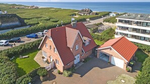 A large brick house with a red roof, a garage, and a driveway. - Haus am Strand, Beachfront - Strand, Meer & Luxus (Wenningstedt-Braderup (Sylt))
