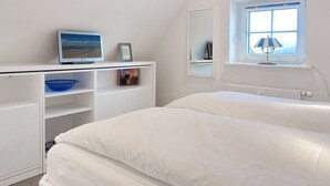 A bedroom with a bed, a desk with a computer, a window with a lamp, and a view of the sea. - Am Kurpark, App. 4 - Wohlfühl-appartement in Bester Lage. Nur Wenige Meter zum Strand (Wenningstedt-Braderup (Sylt))