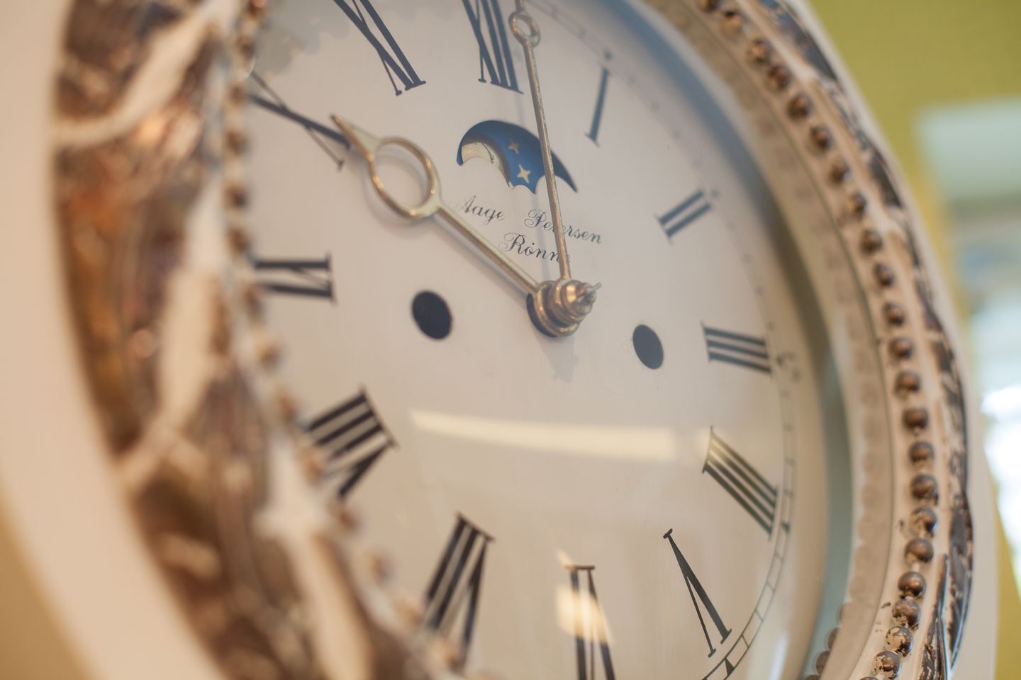 Un primer plano de la esfera de un reloj con números romanos y un símbolo de luna, mostrando una hora específica.
