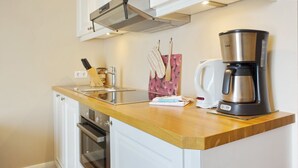 Eine Küche mit weißen Schränken, einer Edelstahl-Kaffeemaschine und einer Holzausziehtafel.