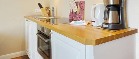 A kitchen with white cabinetry, a stainless steel coffee maker, and a wooden countertop.