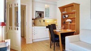 A compact living space with a kitchenette, dining area, and a small seating area. - Haus Silvana, App. 3 - 1-raum Appartement mit ca. 25m ² Nutzfläche im Erdgeschoss (Wenningstedt-Braderup (Sylt))
