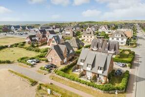 A residential area with houses, a parking lot, and a view of the sea. - Am Kurpark, App. 3 - 2-raum-appartement im Erd- und UG mit ca. 53m² Nutzfläche für Max. Zwei (Wenningstedt-Braderup (Sylt))