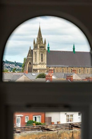 A church with a prominent spire and two green towers, viewed through a circular window.