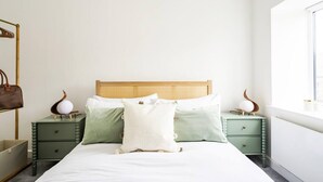 Une chambre à coucher avec un lit, deux tables de chevet, une commode et une fenêtre.