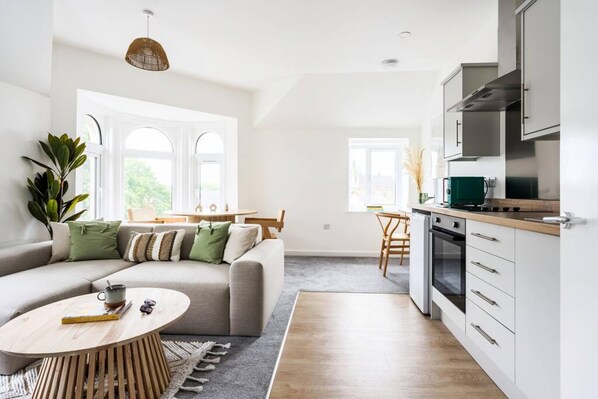 Ett modernt vardagsrum med en soffa, ett soffbord och en matplats med ett bord och stolar.