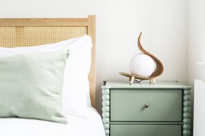 A bed with white bedding, a green nightstand with a drawer, and a decorative object on top.
