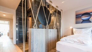 Un dormitorio moderno con una cama grande, una pared de acento de madera e instalación original de cuerdas.