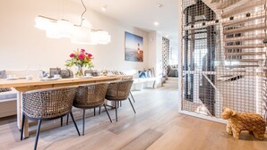 Un comedor moderno con una mesa de madera, sillas de mimbre y un jarrón decorativo.