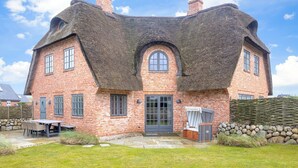 A brick house with a thatched roof, a stone wall, and a small garden. - Strandhaus - Hausteil im Eg,ug,og,dg ca. 157qm Nutzfl., Nichtraucher, Haustiere Nicht Erlaubt (Wenningstedt-Braderup (Sylt))