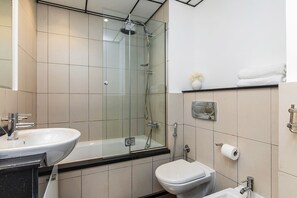 A modern bathroom with a glass-enclosed shower, a white sink, and a toilet. - The Jewels Tower (Dubai)