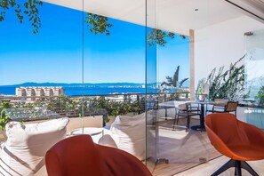 A balcony with a view of the sea, a table, chairs, and a glass partition.