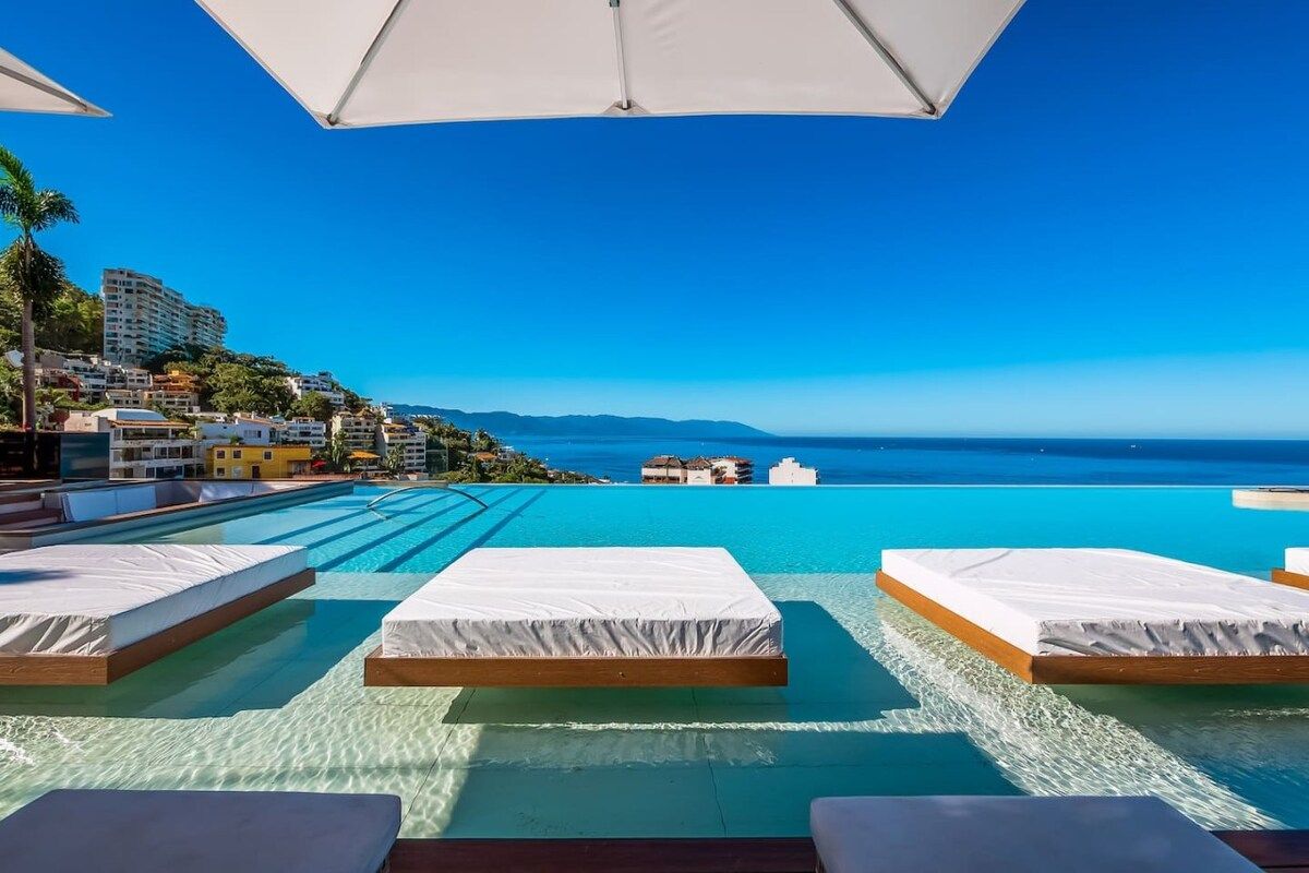 A poolside area with lounge chairs and a view of the ocean.