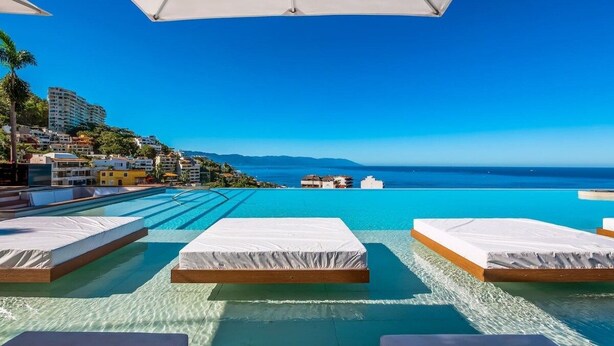 A poolside area with lounge chairs and a view of the ocean.