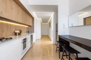 A modern kitchen with white cabinetry, a black countertop, and a wooden accent wall.