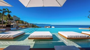 A poolside area with lounge chairs and a view of the ocean.