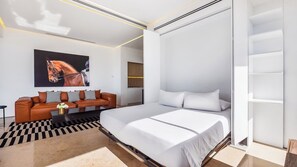 A modern bedroom with a large bed, a sofa, and a painting of a horse.