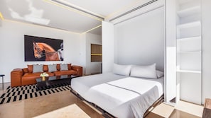 A modern bedroom with a large bed, a sofa, and a painting of a horse.
