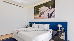 Un dormitorio con una cama grande, un cabecero azul y un cuadro de un caballo colgado en la pared.