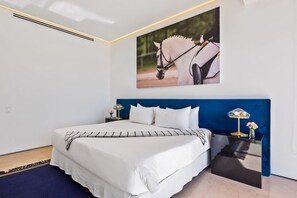 A bedroom with a large bed, a blue headboard, and a wall-mounted picture of a horse.