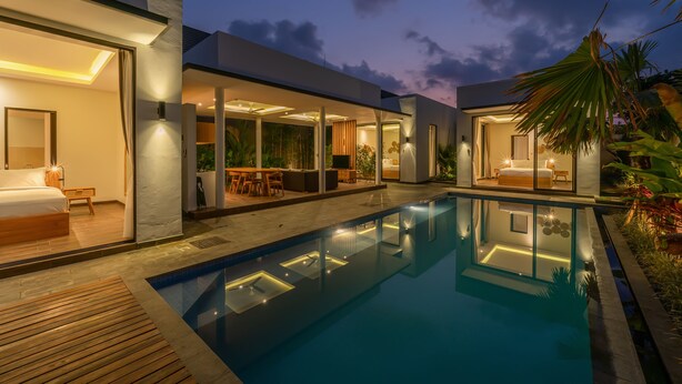 Et moderne hus med swimmingpool, store glasdøre og et veloplyst interiør.