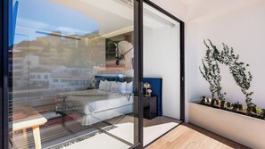 A modern bedroom with a glass door, a bed, a nightstand, and a wall-mounted plant.