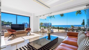 Un salón moderno con una mesa de centro de cristal, sofá de cuero y un televisor de pantalla plana.