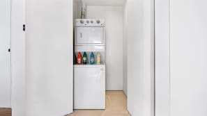 A narrow hallway with a white refrigerator stocked with cleaning products.