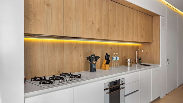 A modern kitchen with white cabinets, a stainless steel stove, and wooden wall paneling.
