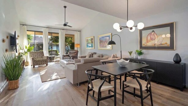 Una sala de estar moderna con comedor, ventanas amplias y un ventilador de techo.