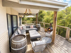 Una terraza techada al aire libre con sofá, sillas, una mesa, un hogar para fuego y una pérgola.