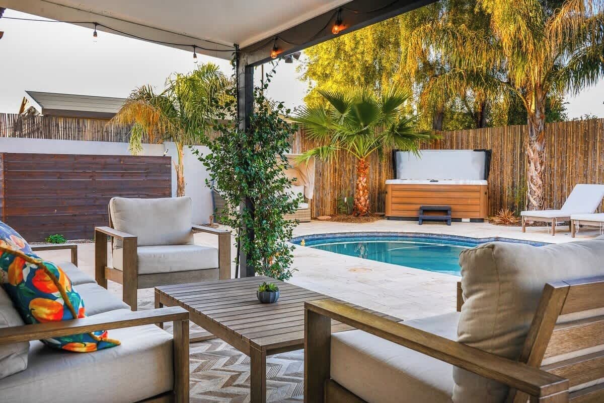 An outdoor patio with a pool, seating area, and a wooden fence.