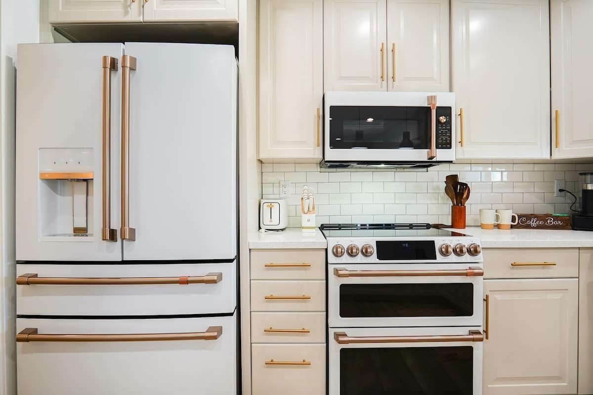 A kitchen with a white refrigerator, a microwave, an oven, and a coffee bar sign.