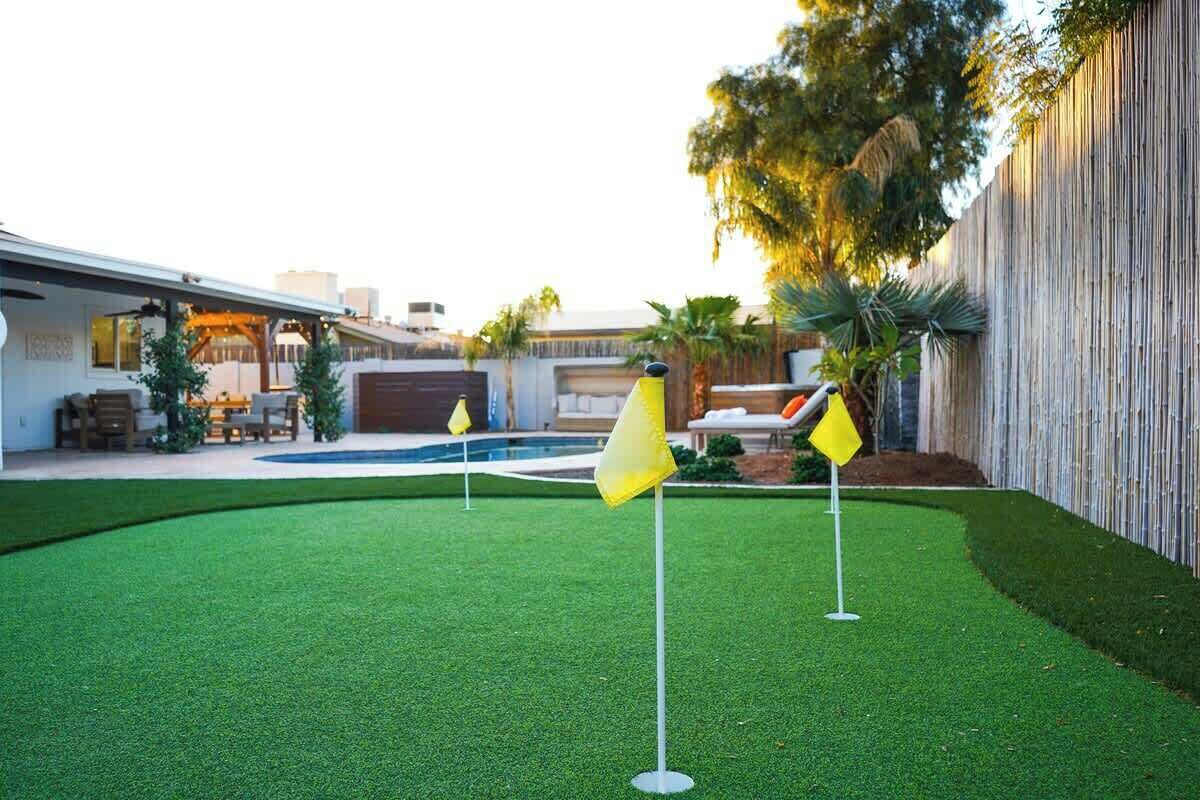 Patio con césped artificial, piscina y cerca de madera.