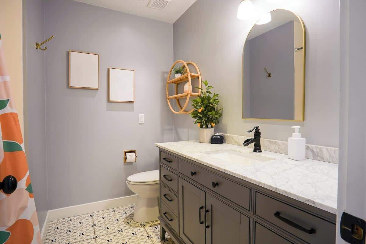 A bathroom with a toilet, a sink with a mirror, a towel rack, and a potted plant.
