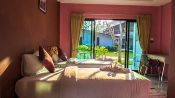 Habitación de hotel con dos camas, un escritorio y vistas a un jardín y edificios.
