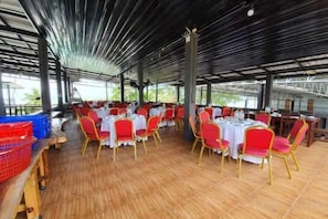 Un espacio de comedor al aire libre con techo, con mesas y sillas dispuestas para los huéspedes.