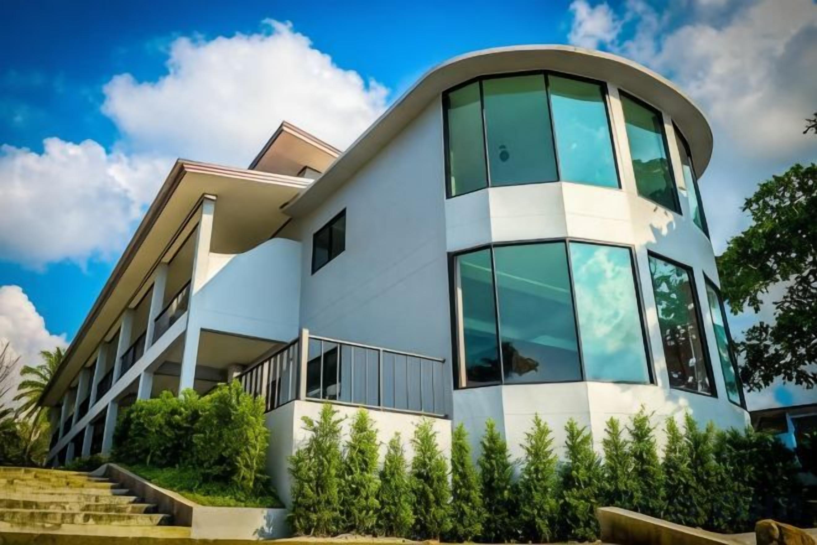 Un edificio moderno de varios pisos con grandes ventanales y una fachada curva.