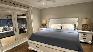 A bedroom with a bed, two bedside tables with lamps, a ceiling fan, and a sliding glass door leading to a balcony. - New Beach Cabana with Mini Golf (Venice)