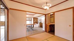 Ett traditionellt japanskt rum med tatamimattor på golvet, ett träpanelat tak och skjutdörrar.