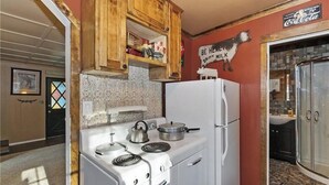 Una cocina con electrodomésticos blancos, armarios de madera y un letrero de Coca-Cola.