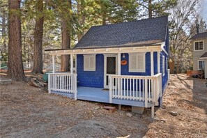 Une petite cabane à un seul étage, avec un toit sombre, des balustrades blanches et une façade bleue.