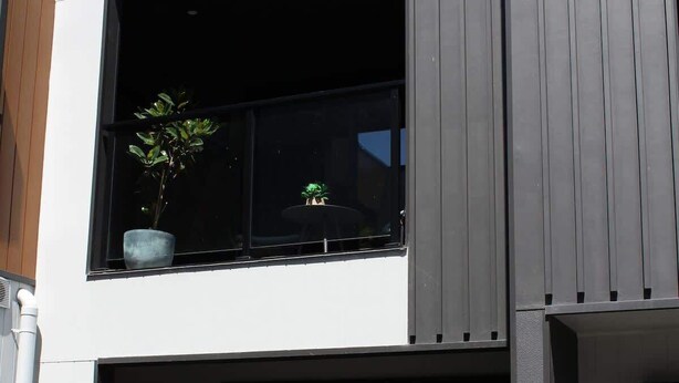 A modern two-story building with a garage, a potted plant on the balcony, and a visible number '7' on the wall. - CBD Elizabeth St Modern Townhouse - Secure Parking (Launceston)