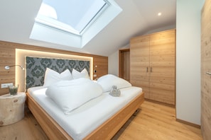 A modern bedroom with a skylight, wooden headboard, and a built-in wardrobe.