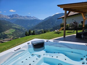Ein Whirlpool mit Blick auf die Berge, eine Holzhütte und ein Stuhl.