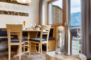 A dining area with wooden chairs and a table, a bottle of water, and a menu sign.