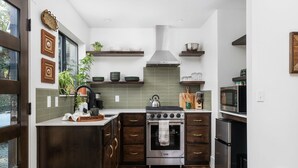 A modern kitchen with dark wood cabinets, a stainless steel stove, and a microwave. - Manzanita Rest (Mariposa County)