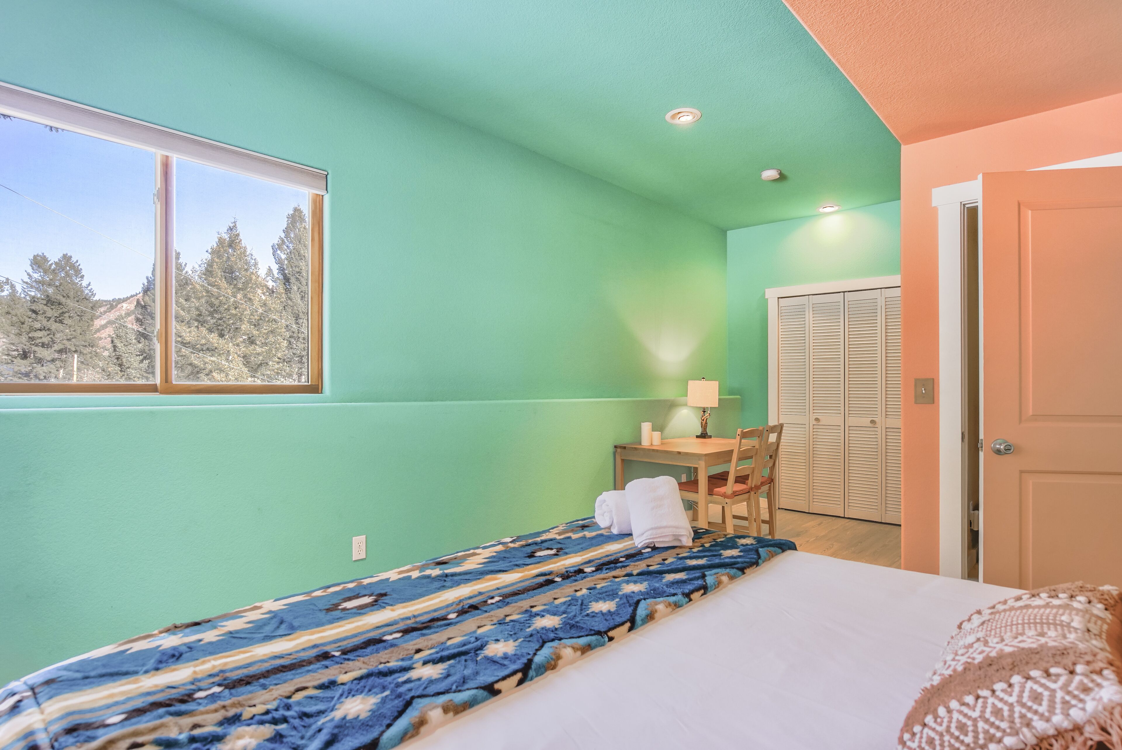 Quarto com uma cama, escrivaninha, cadeira, janela e porta.