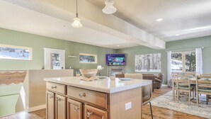 A spacious living area with a kitchen island, wooden cabinets, and a dining set. - Peekaboo Mountain (Cascade)